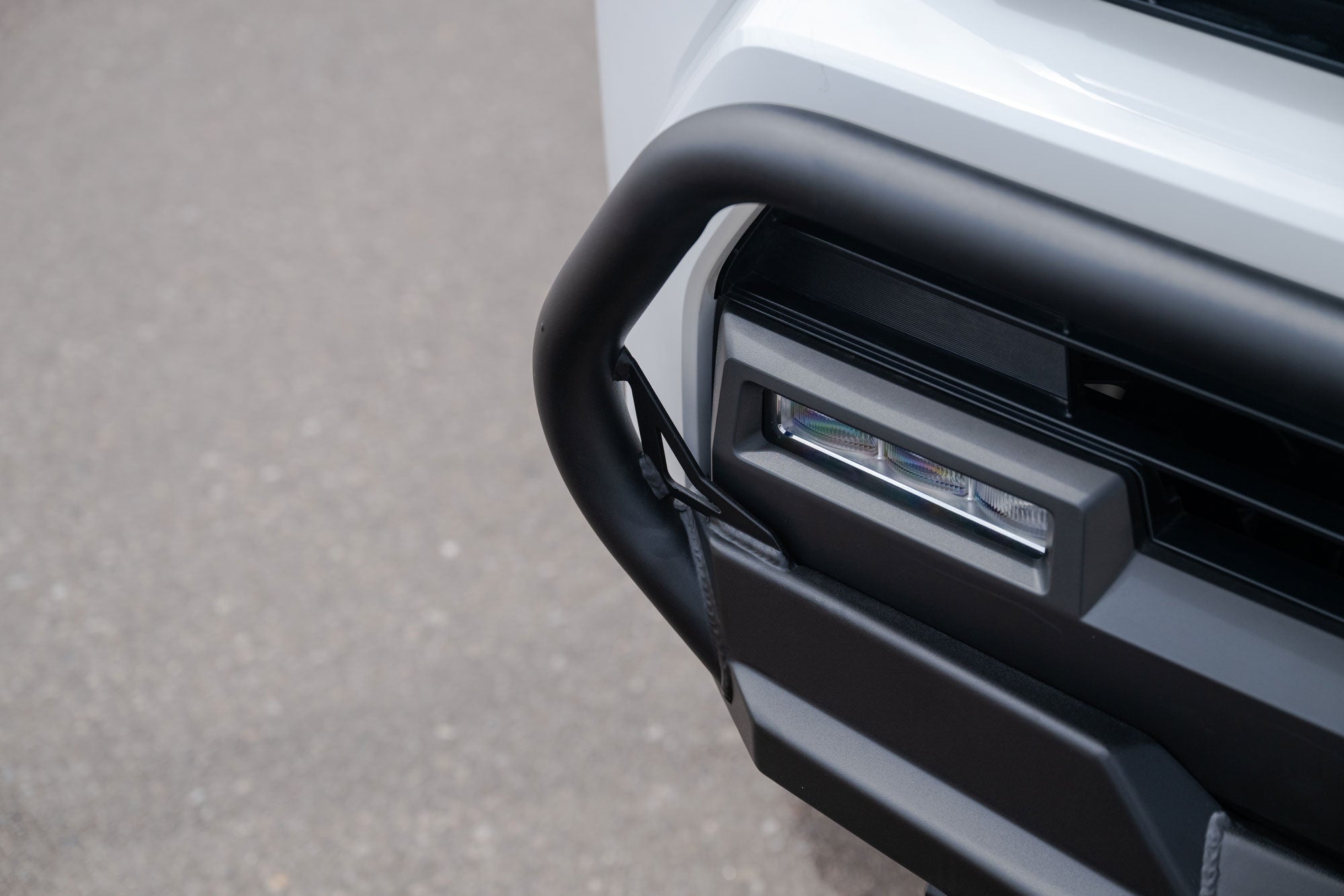Close-up of a car's front bumper and grille on a gray pavement background