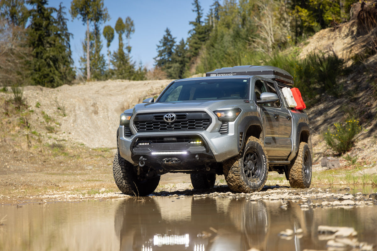 Toyota truck driving through a muddy area with trees in the background