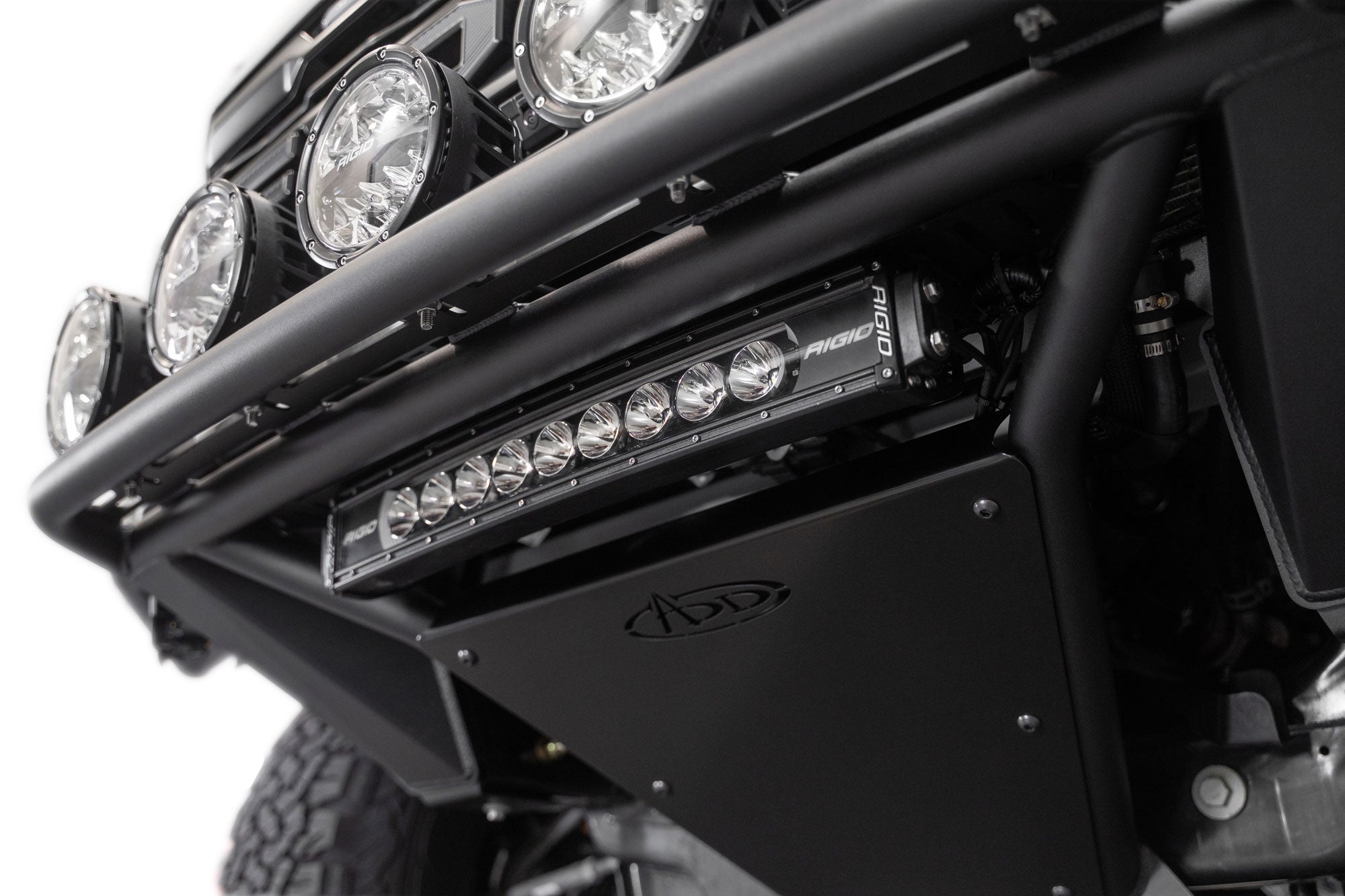 Low-angle view of the 2021+ Ford F-150 Raptor Pro Plus Frame Cut Front Bumper skid plate installed with Rigid lightbar