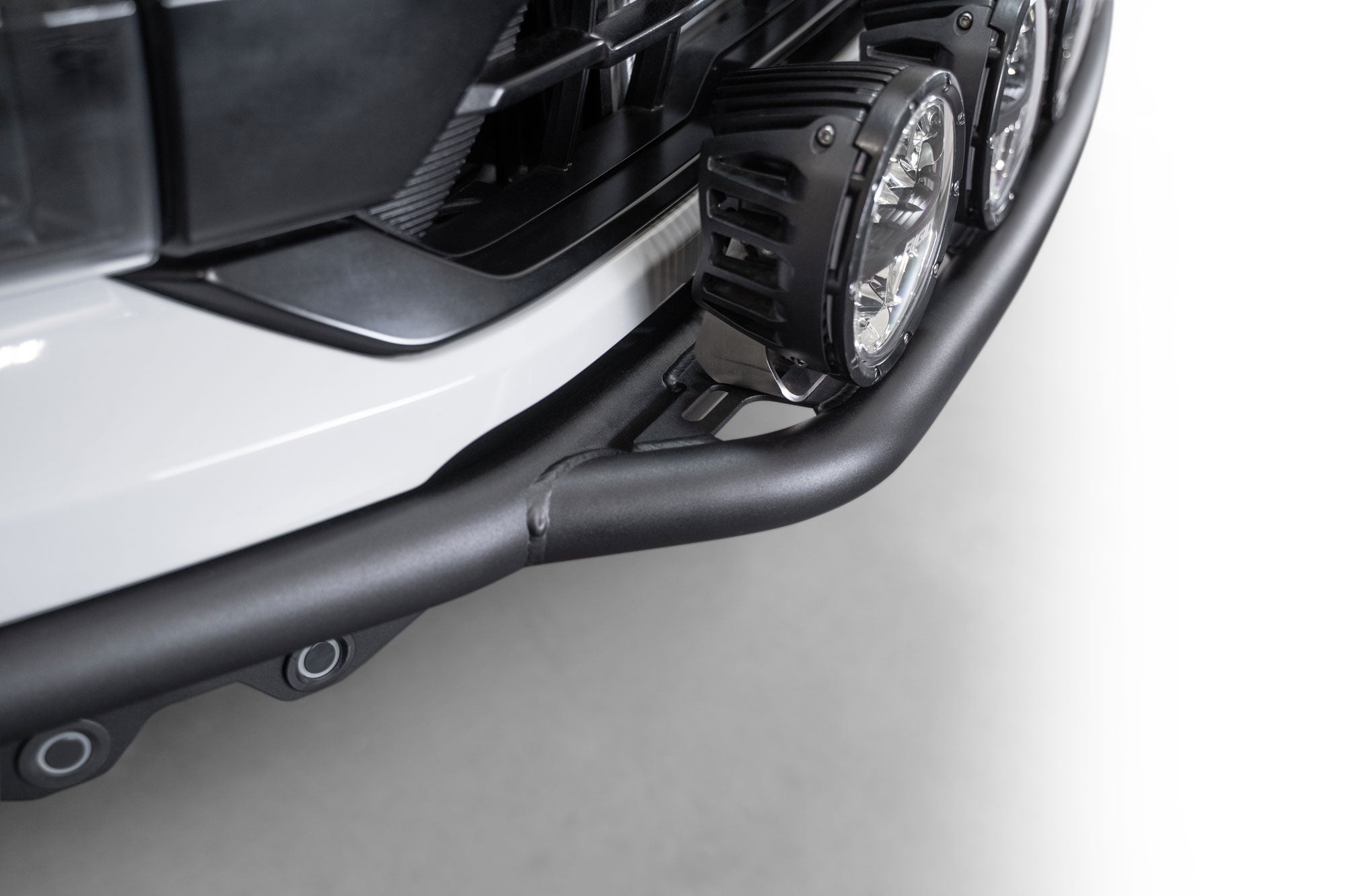 Top-down close view of installed 2021+ Ford F-150 Raptor Pro Plus Frame Cut Front Bumper showing OEM sensor relocation and round off road lights mounted 