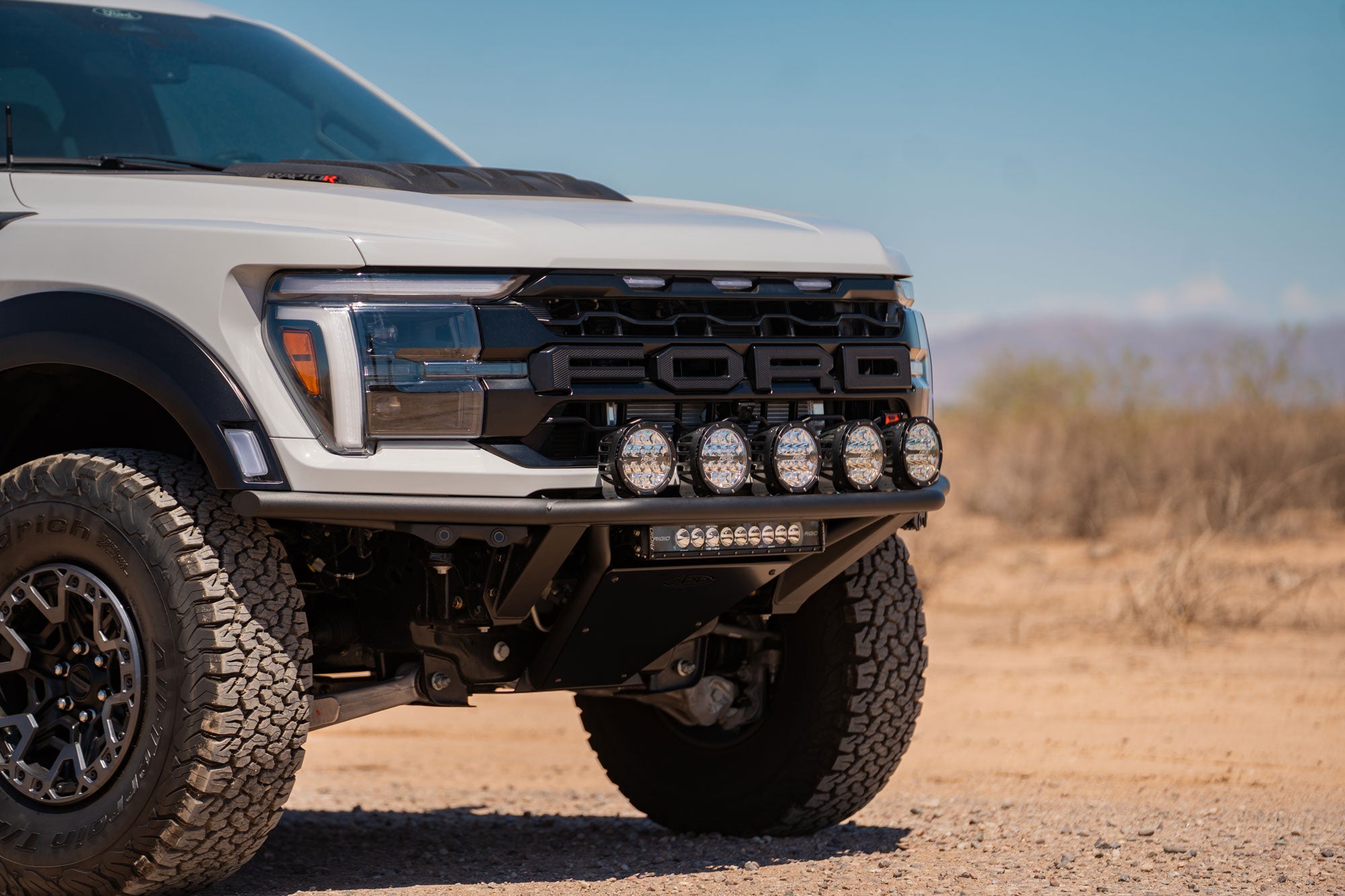Front-angle view of installed 2021+ Ford F-150 Raptor Pro Plus Frame Cut Front Bumper showing the skid plate and as much clearance as you can get