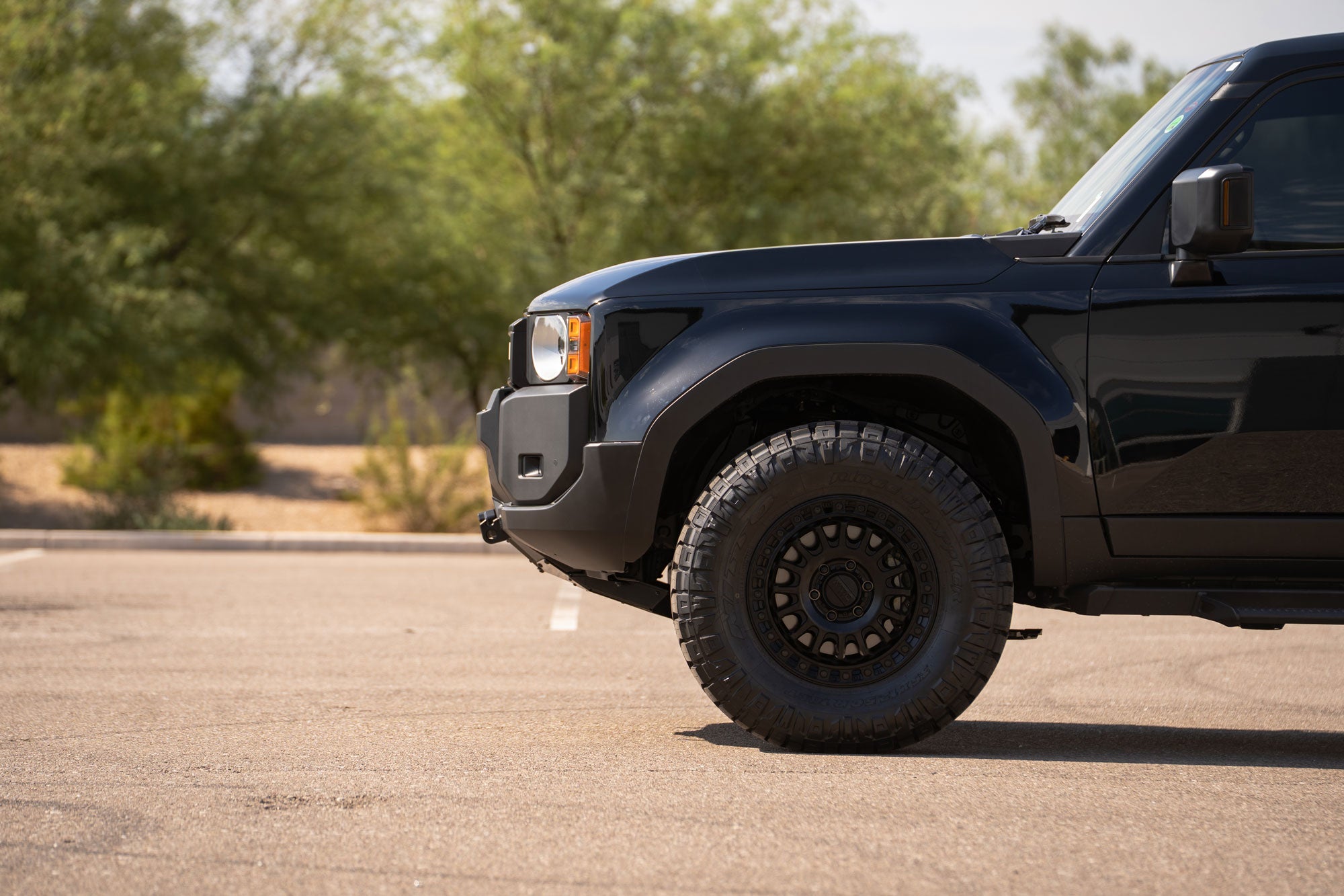 Side profile view of Toyota Land Cruiser in parking lot with the Stealth Center Mount Winch Front Bumper for 2024+ vehicles installed