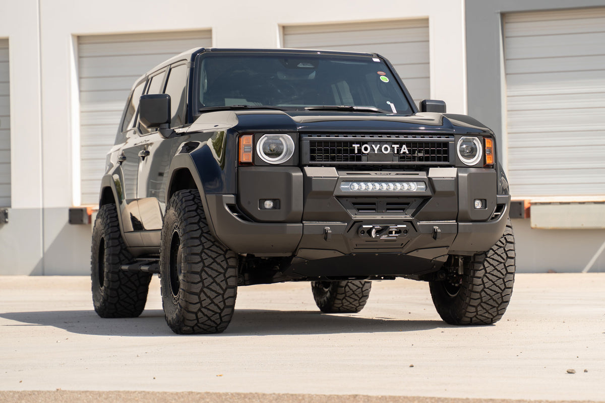 Toyota Land Cruiser parked in front of industrial building with Center Mount 250 Series Front Winch Bumper installed