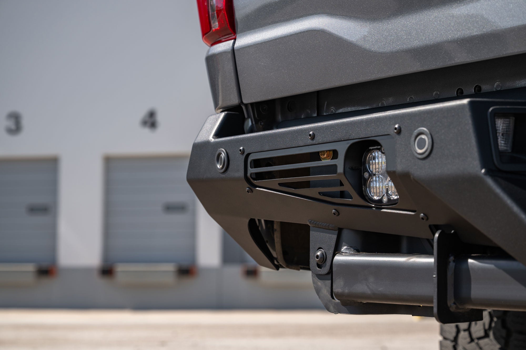 Angled close-up view of installed 2024+ Ford F-150 Bomber Rear Bumper with extra rear lighting, oem sensor functionality, integrated wire management for clean install